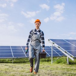Man worker in the firld by the solar panels